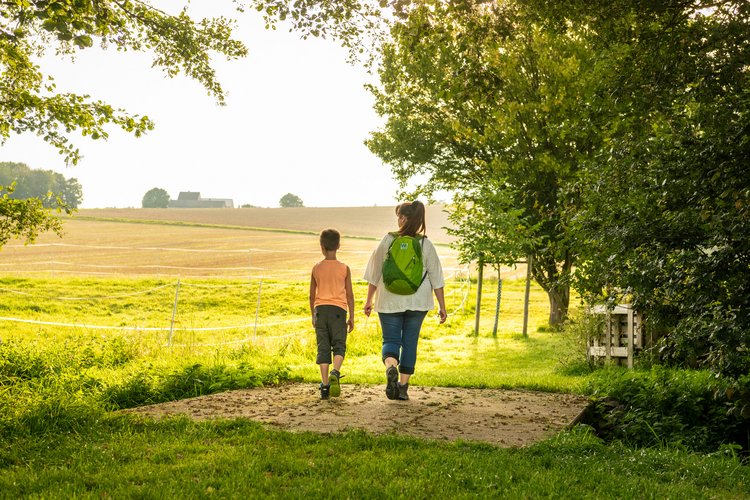 Eine Frau läuft mit einem Jungen im Sommer über ein Feld 