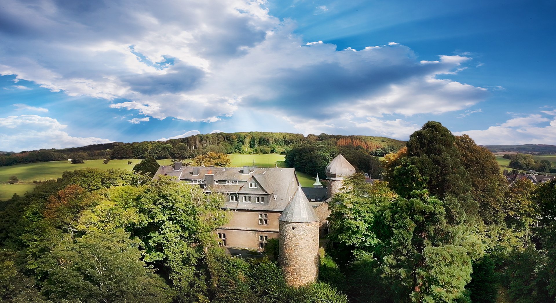 Zwischen den Baumwipfel erhebt sich Schloss Friedewald in den blauen Himmel