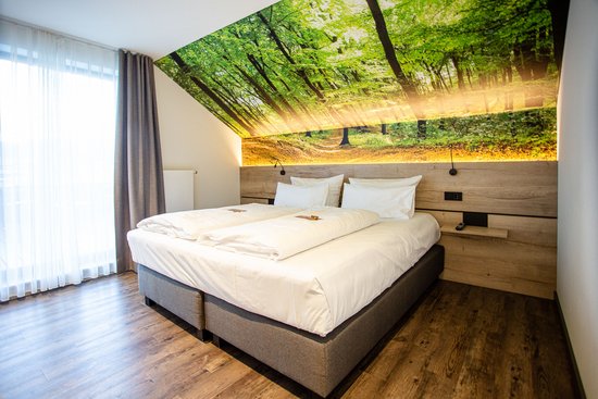 Hotelzimmer mit Doppelbett mit Waldkulisse als Fototapete