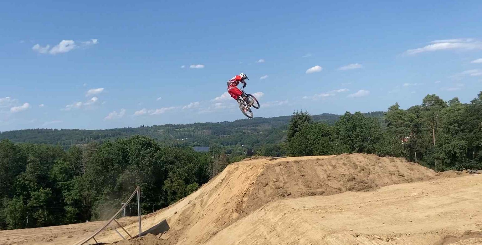 Ein Mountainbiker springt über einen Hügel